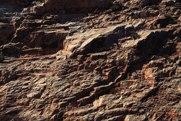 Grungy cragged bumpy pitted cavity stone facade, split layer gap.Ruined cracked shattered worn rough hiking canyon.Old ragged grunge steep marble cliff. Grand vintage crannied damaged impressive gorge