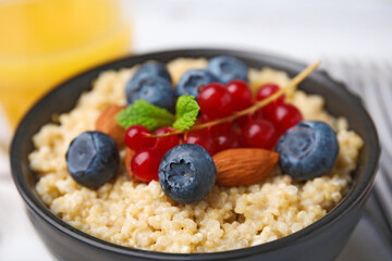 Bowl of delicious cooked quinoa with almonds, cranberries and blueberries, closeup