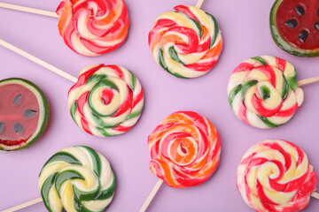 Many different lollipops on violet background, flat lay