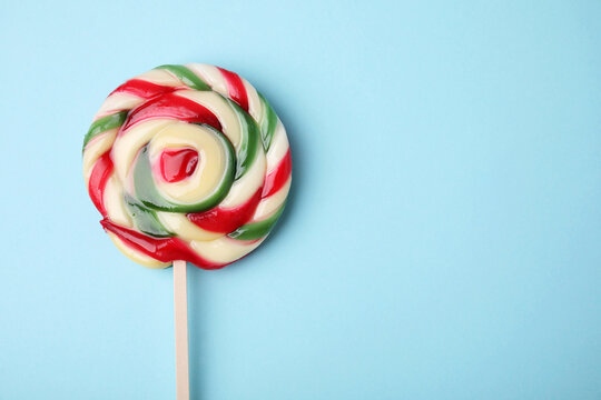 Colorful lollipop on light blue background, top view. Space for text