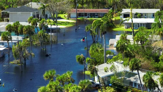 Kayak boat floating on flooded street surrounded by hurricane Ian rainfall flood waters homes in Florida residential area. Consequences of natural disaster