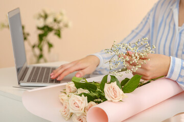 Obraz na płótnie Canvas Woman making bouquet following online florist course at home, closeup. Space for text