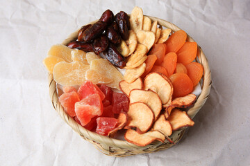 Wicker basket with different dried fruits on paper