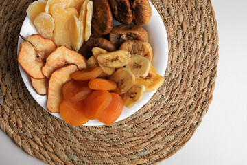 Bowl with different dried fruits on white background, top view