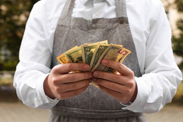 Waiter holding tips in outdoor cafe, closeup