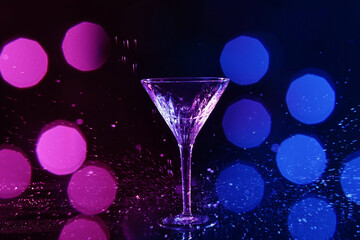Martini glass and splashes in neon lights on dark background, bokeh effect