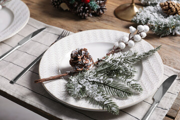 Plate with cutlery and festive decor on wooden table