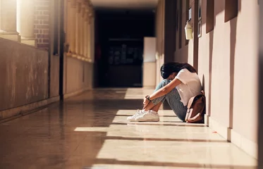Fotobehang Sad, lonely and girl with depression at school, crying and anxiety after bullying. Mental health, tired and unhappy student in the corridor after problem in class, education fail and social isolation © D Lahoud/peopleimages.com