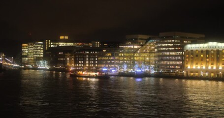 River banks shot panning towards Tower bridge. Tower Bridge over Thames river in London England UK Great Britain in Europe at night dark sky - Powered by Adobe