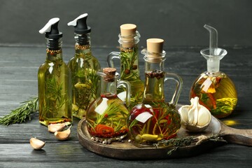 Obraz na płótnie Canvas Cooking oil with different spices and herbs in bottles on grey wooden table