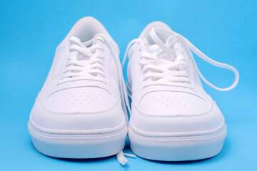 A pair of white sneakers on a blue background, flat lay