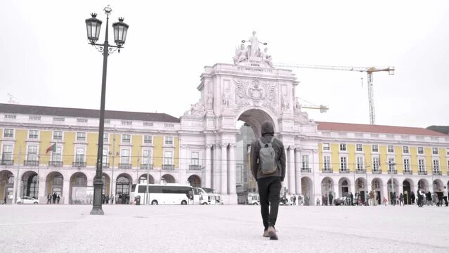 A young man is walking carrying a bag in Commerce Square, Portugal