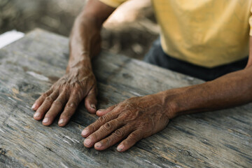 Close up of male wrinkled hands, old man is wearing on the wood table