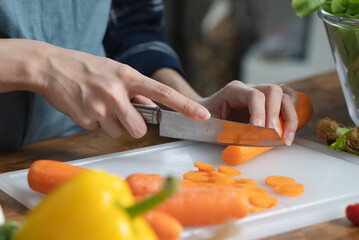 Asian housewife woman slice carrot to preparing salad ingredients for dinner meal  in the kitchen