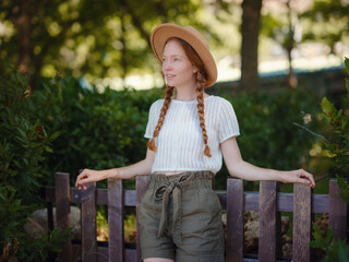 Caucasian ginger young beautiful woman in hat traveling alone. Attractive traveler look around and explore while walk in nature wood with happiness and fun during holiday vacation trip.