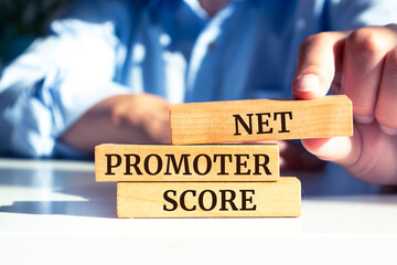 Closeup on businessman holding a wooden blocks with text NET PROMOTER SCORE, business concept