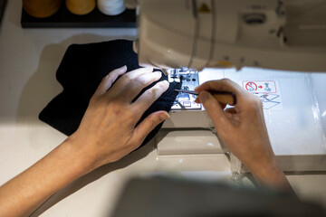 재봉틀로 옷감을 박음질하는 여자의 손