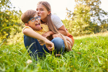 Schwester ärgert ihren Bruder auf einer Wiese