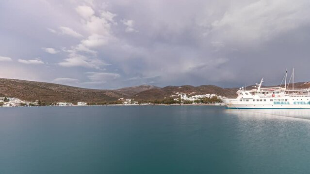 Panorama showing Amorgos island timelapse at evening during sunset. Traditional Greece - white houses on hills and ship in sea port in harbor, Cyclades
