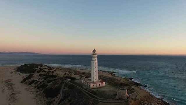 Drone approaching the Trafalgar lighthouse post sunset with the dark blue ocean on coast of Cadiz Spain