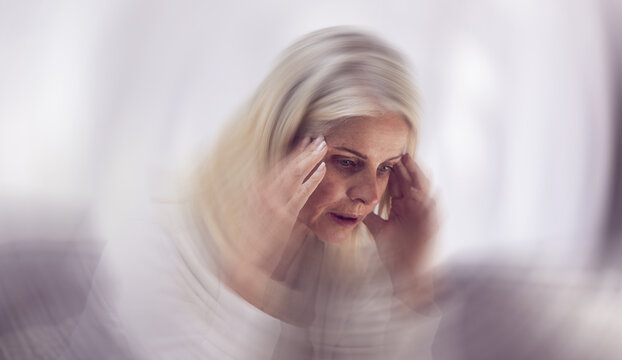 Senior woman, headache and dizzy motion blur on sofa for mental health, stress and health risk. Elderly person, tired and suffering from migraine for dementia crisis or head pain in retirement home
