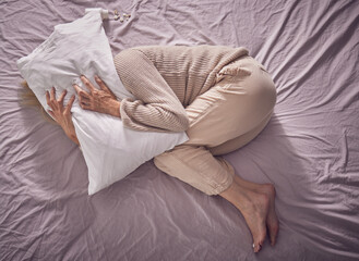Top view, depression and sad woman with pillow, bedroom and insomnia, anxiety problem and crying. Depressed, tired and sick lady in sleepless night, fear and mental health stress, scared and burnout