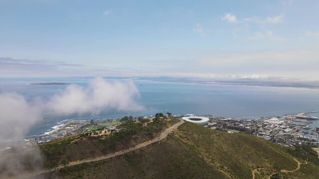 Small clouds above the signal hill and the Cape Town city stadium visible in the background