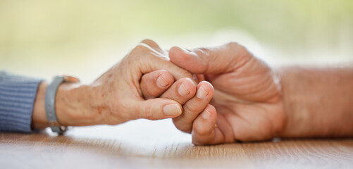 Elderly couple, holding hands and support for comfort, love or help on table for compassion, pain...