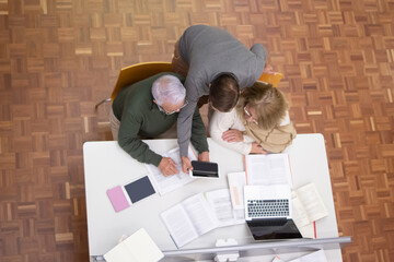 Top view of senior people studying in library. Concentrated man and woman sitting at table with...
