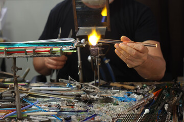 Glassworker while shaping the glass with a very high temperature flame in its artisan workshop in Venice. Italy