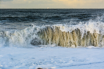 violent steep waves crashing onto a sandy beach during winter. Shot in Denmark