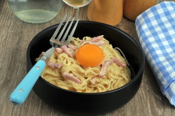 Assiette de spaghetti carbonara avec un jaune d'oeuf et une fourchette
