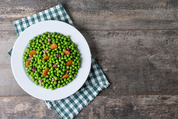 Green peas with serrano ham and carrot on wooden table. Top view. Copy space