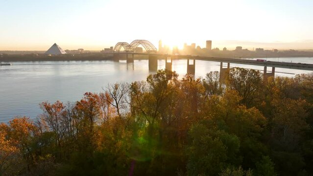 Memphis Tennessee aerial establishing shot of city skyline at dawn. Rising aerial in golden hour beautiful warm light. Mississippi River view with Hernando de Soto bridge.