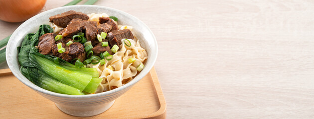 Beef noodle soup. Taiwanese famous food in a bowl on wooden table.