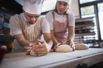 Man with down syndrom helping prepair bread in bakery with his colleague. Concept of integration...