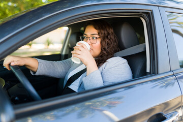 Busy overweight woman driving and drinking coffee