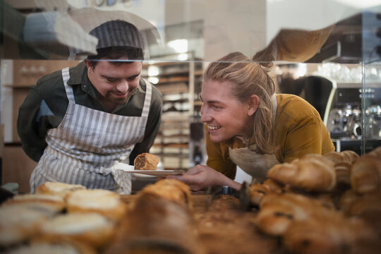 Man with down syndrom helping his colleague in a cafe. Concept of integration people with a disabilities into society.