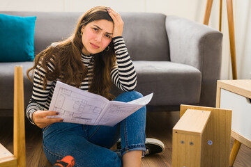 Obraz premium Stressed woman assembling furniture having problems
