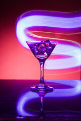 Martini glass with ice. On the bar. Against the background of neon light.