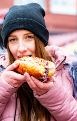 Young Woman Eating Hot dog. Street food outdoor winter