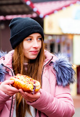 Young Woman Eating Hot dog. Street food outdoor winter