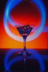 Martini glass with ice. On the bar. Against the background of neon light.
