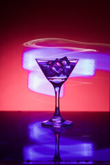 Martini glass with ice. On the bar. Against the background of neon light.