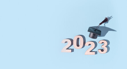 Class of 2023 concept. Numbers 2023 with black graduated cap on colored background