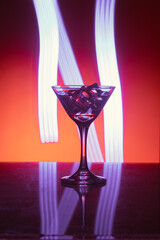 Martini glass with ice. On the bar. Against the background of neon light.