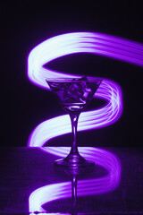 Martini glass with ice. On the bar. Against the background of neon light.