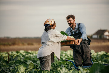 Cropped shot of a young farm couple carrying a crate of fresh produce. Dedicated working couple in...