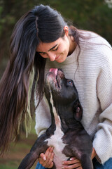 Young caucasian woman laughing after her american staffordshire and french bulldog mixed breed dog...