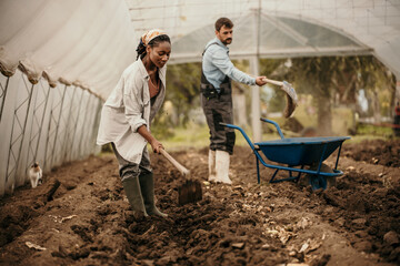 Shot of a young female farmer working with her husbant in their greenhouse.